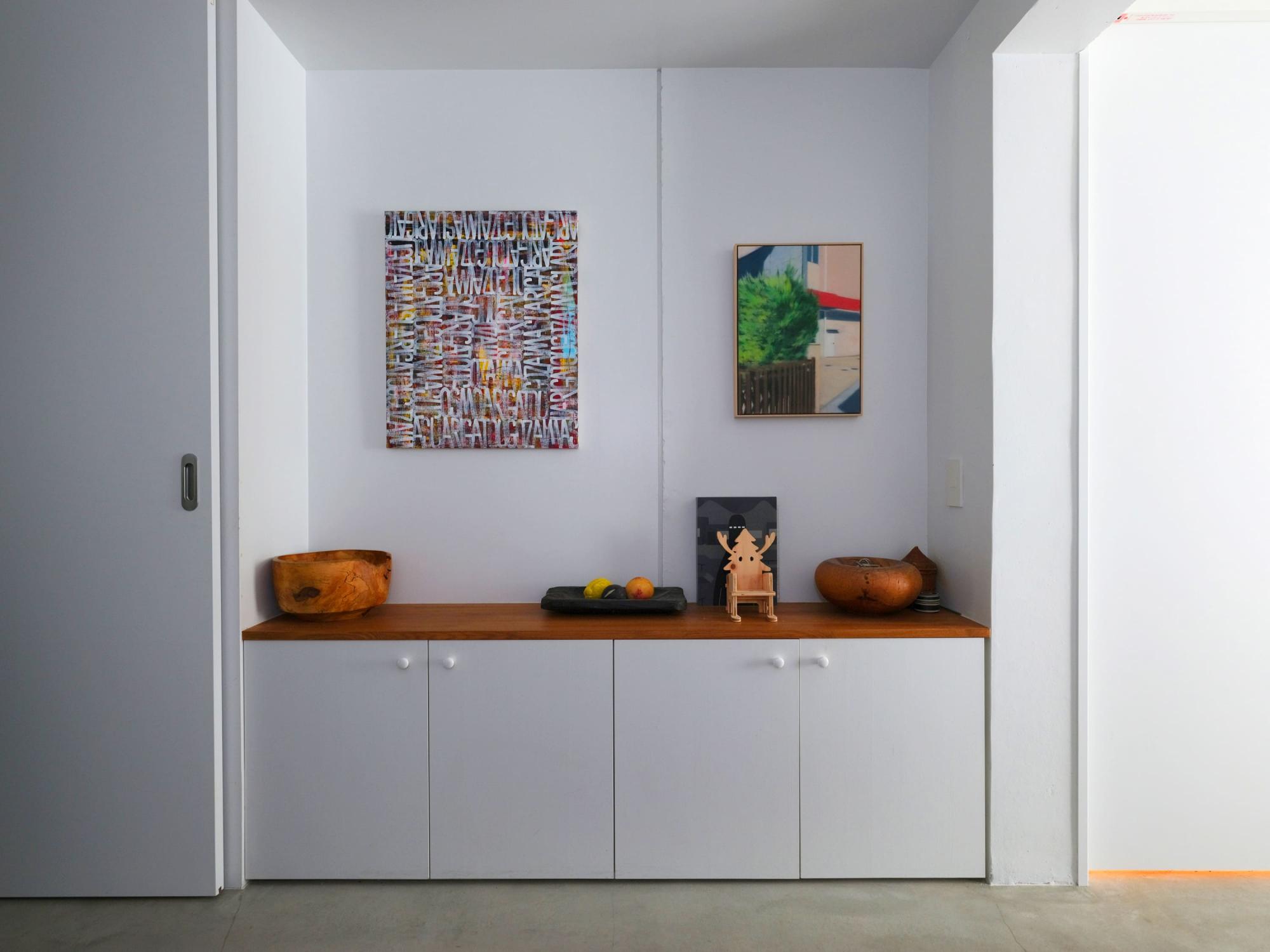 お部屋に入った瞬間に見える廊下の収納兼ディスプレイ。
モルタルの床と塗装の壁というシンプルなしつらえにはアートが良く映えます。