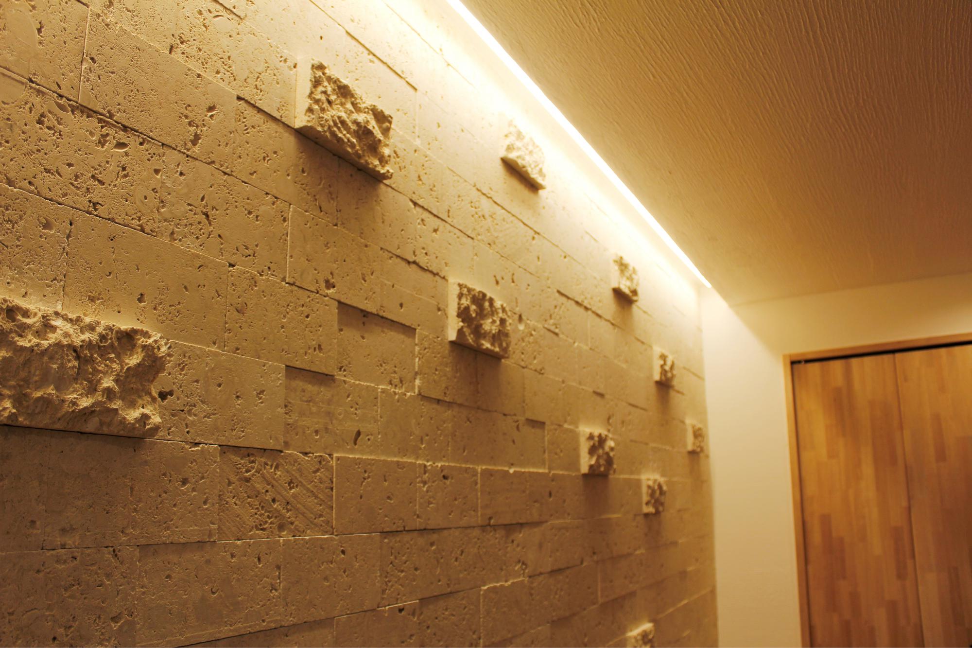 天然石の凹凸を活かしてデザインしたリビングの壁。間接照明で照らされることで、陰影がうまれます。