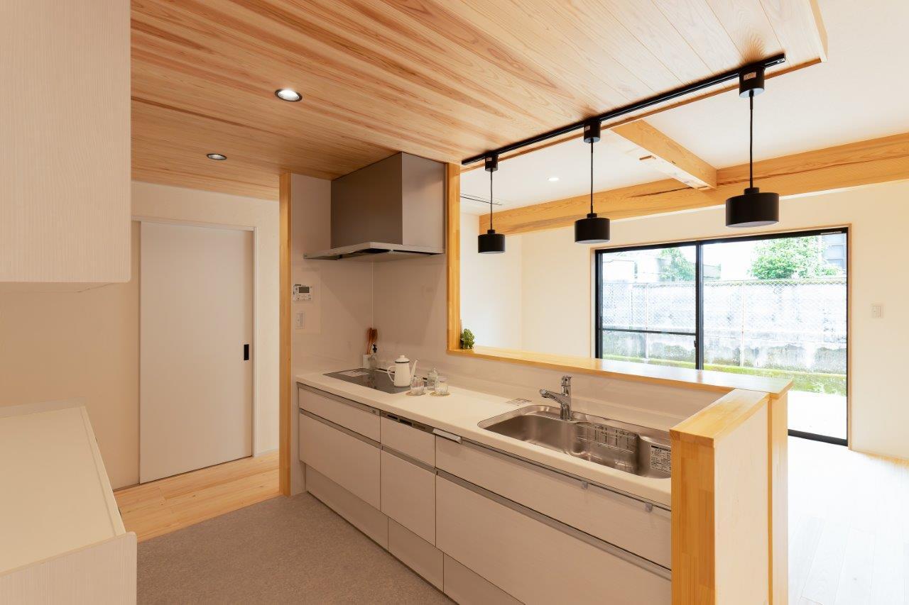機能性とデザイン性を兼ね備えた、洗練されたキッチン空間。
木の天井がやさしい温もりを添え、シンプルで美しい直線的なデザインが空間全体を引き締めています。

対面式のキッチンは、リビングやダイニングとのつながりを大切にした開放的な設計。大きな窓から差し込む自然光が、明るく清潔感のある空間を演出します。