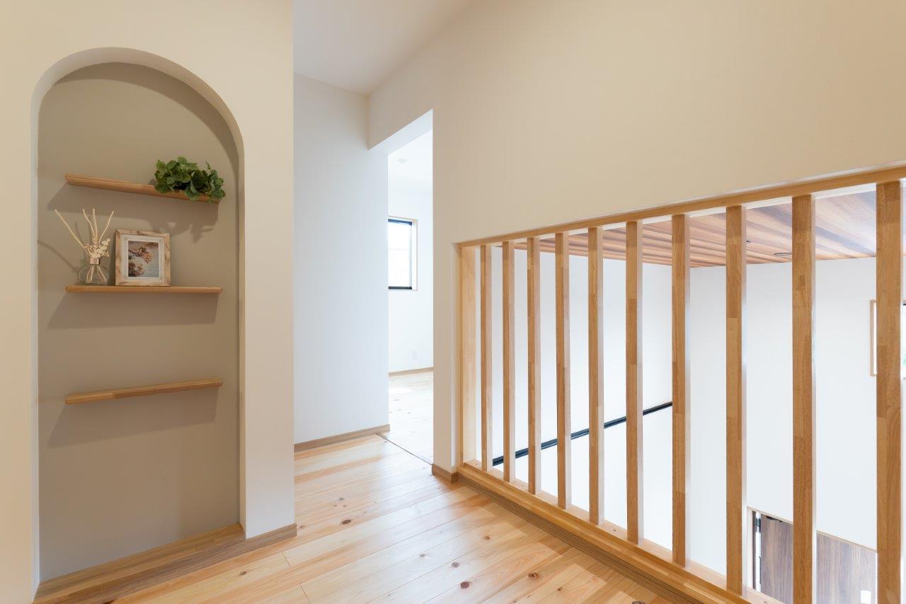 やわらかな光が差し込む開放的な空間に、木の手すりと無垢床が温もりを添える。アーチのニッチがさりげないアクセントとなり、心地よく整った暮らしを演出します。