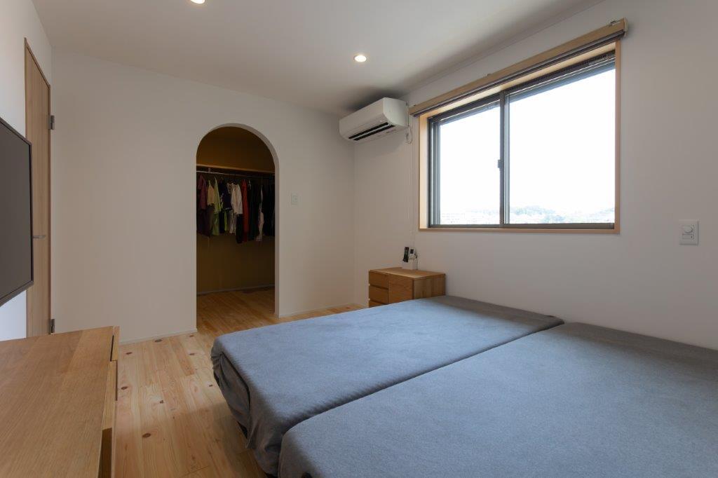 落ち着いた色合いとやわらかな光に包まれた、くつろぎの寝室空間。アーチの開口が空間にやさしいアクセントを添え、シンプルながらも心地よい雰囲気を演出します。