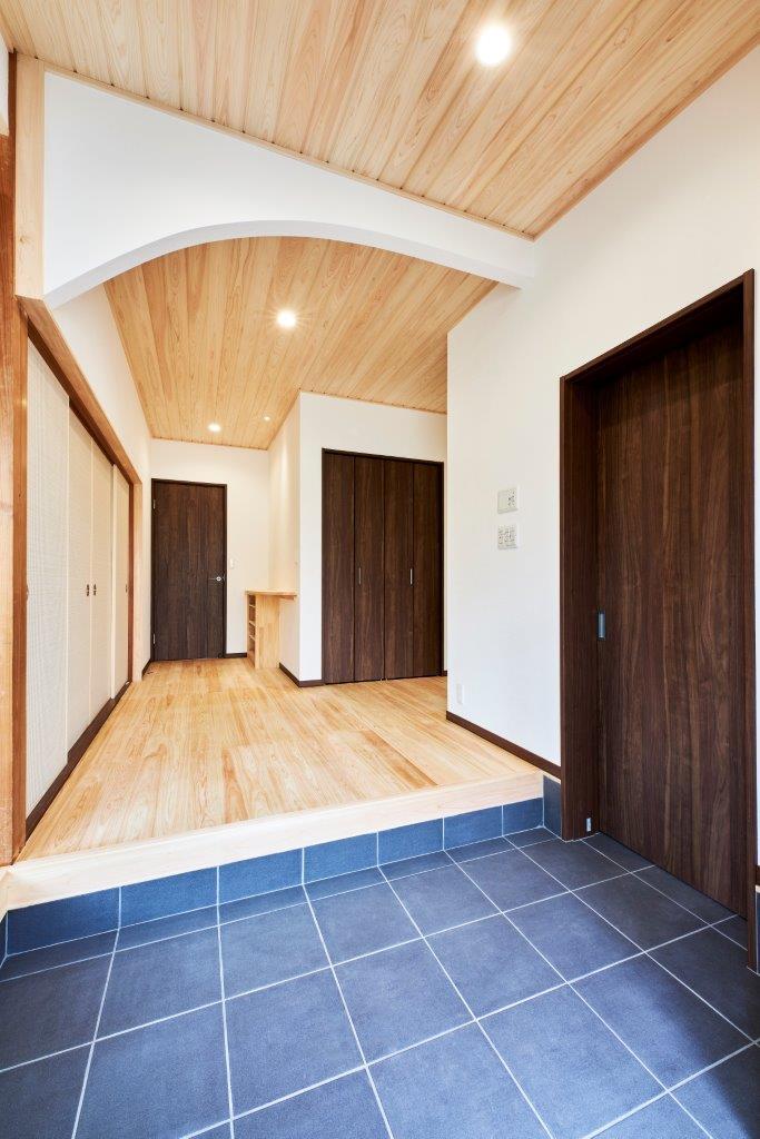 玄関から続く土間と木の空間が、やさしく迎え入れる住まい。勾配天井の広がりと自然素材の温もりが、開放感と落ち着きを兼ね備えた心地よい空間を演出します。