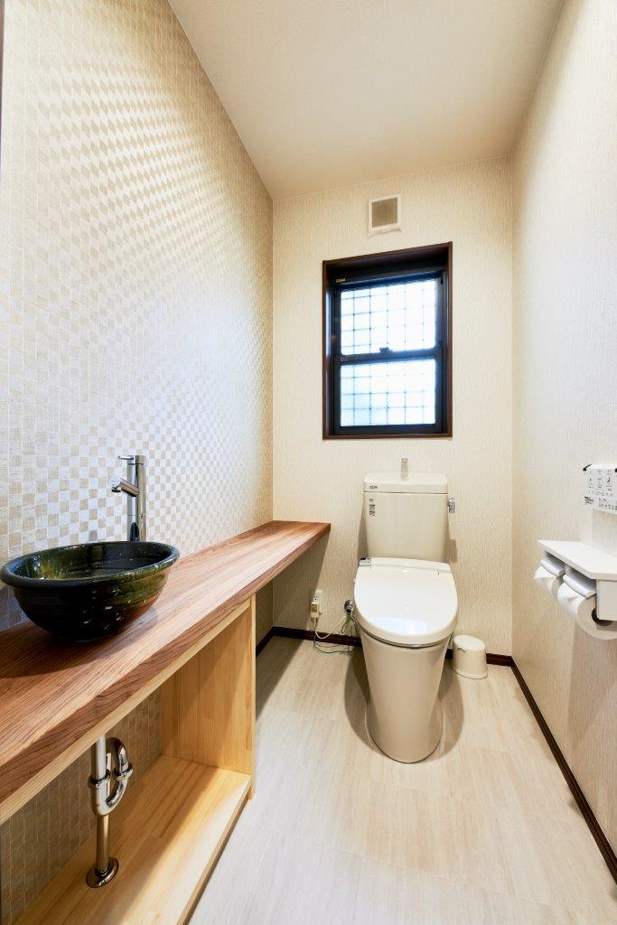 コンパクトながらも使いやすさに配慮したトイレ空間。木のカウンターと手洗いボウルがアクセントとなり、機能性とデザイン性を兼ね備えた心地よい一室です。