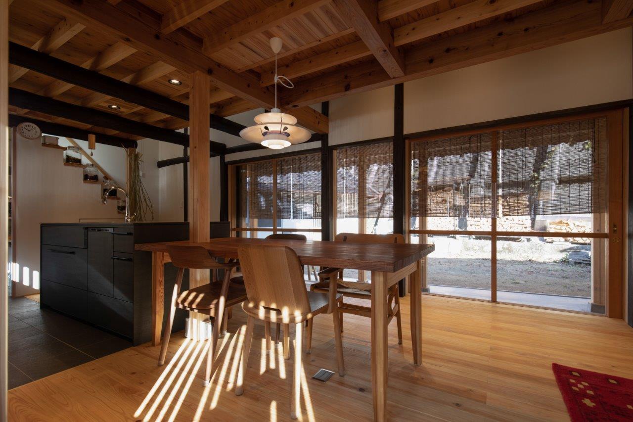 光と木の陰影が美しく調和する、心地よいダイニング空間へと生まれ変わったリフォーム事例です。大きな開口部から差し込む自然光が、無垢材の床や梁にやわらかな表情を与え、時間とともに移ろう豊かな空間演出を実現しています。

ダイニングテーブルを中心に据えたレイアウトは、家族が自然と集まり、会話が弾む暮らしをイメージさせます。キッチンとの距離感も程よく、使いやすさと開放感を兼ね備えた設計が魅力です。

また、外の景色を取り込む大きな窓が、内と外の境界をやわらかくつなぎ、四季の変化を日常の中で感じられる贅沢な空間に。木の温もりと光が織りなす、上質で落ち着いた住まいとなっています。