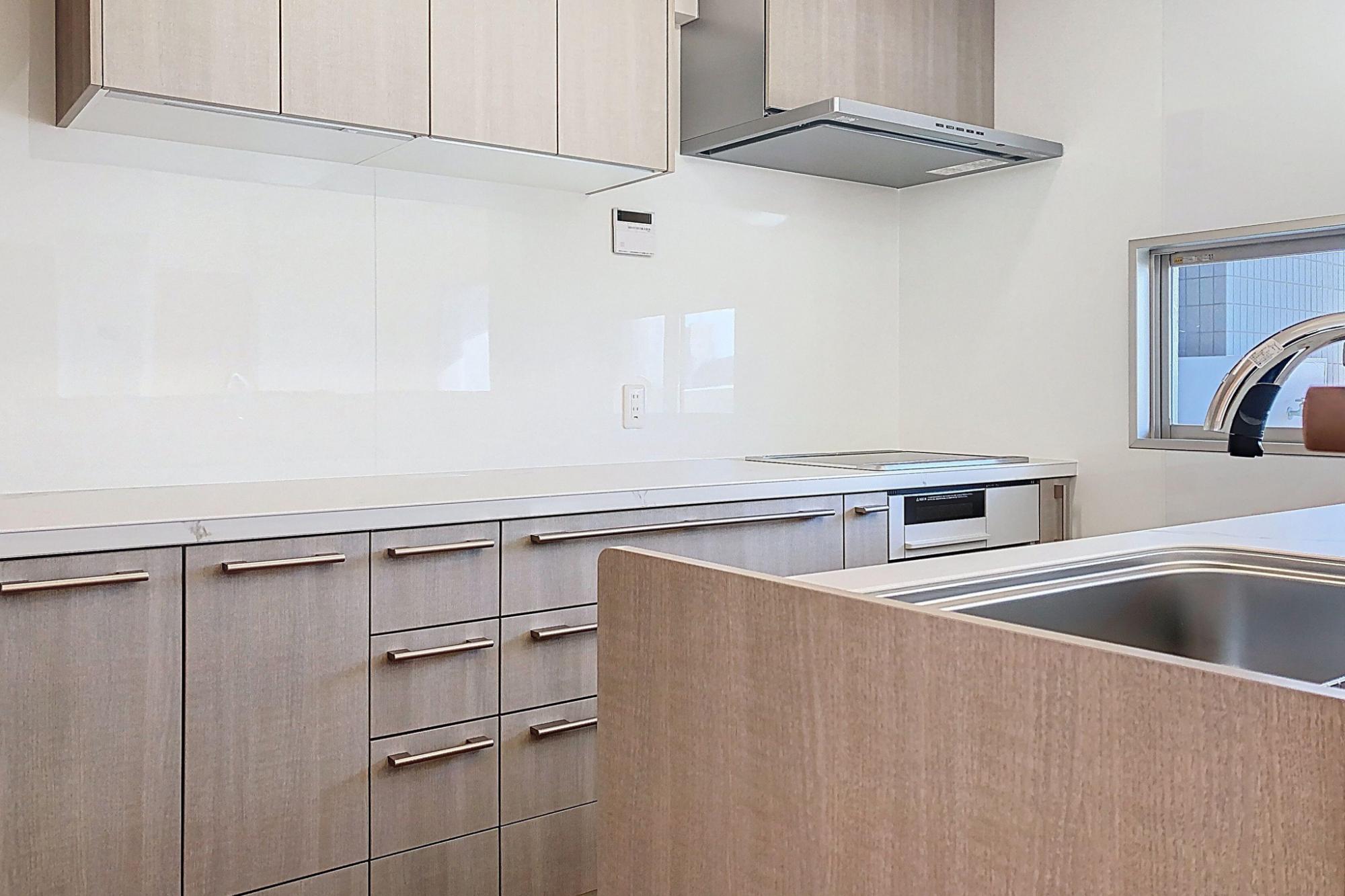 キッチン背面にIHコンロ、カウンター型カップボードを設置。
家電品、ウオーターサーバーなど余裕のある配置が出来ます。
吊戸棚もあり収納力も充実。コンロ前だけでなくカップボード設置壁にもキッチンパネルを貼っています。