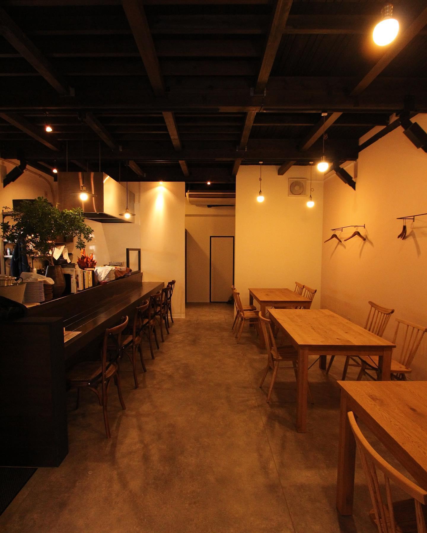 黒く塗装した既存の木造天井と、温かみのあるペンダント照明が印象的な店内です。

カウンター席とテーブル席を通路を挟んで配置し、一人でもグループでもゆったりと食事を楽しめる空間としました。

白い壁と木製家具の柔らかな色合いに、モルタル調の床を組み合わせ、素材の質感を活かしたシンプルなインテリアに。